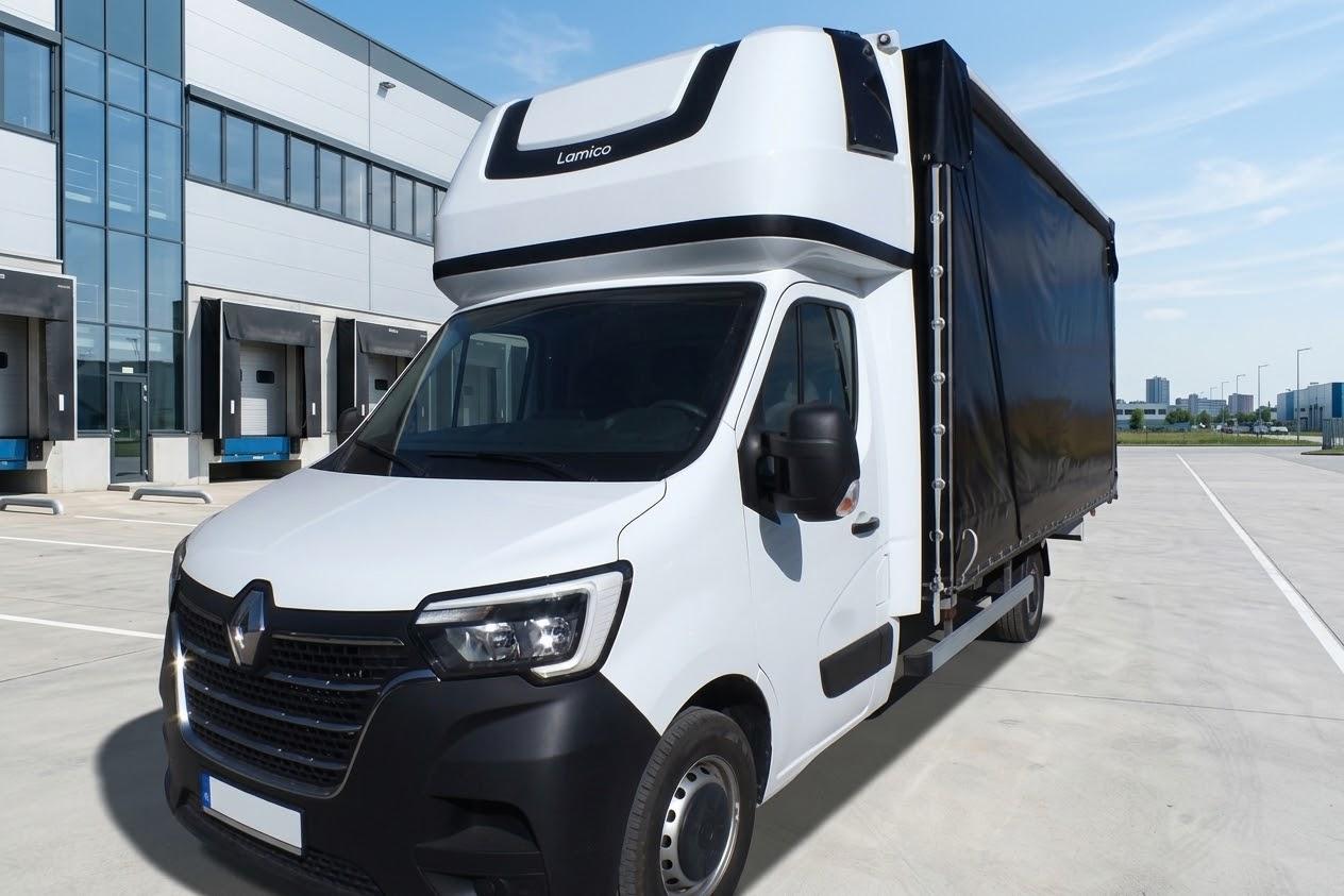 Biały Renault Master z czarną plandeką przed magazynem
